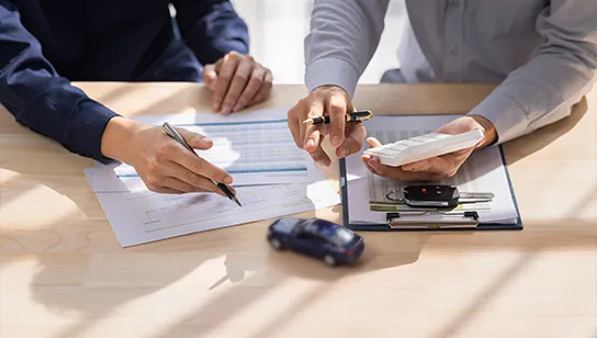 Ein Verkäufer und ein Kunde gehen ein Rechenbeispiel für die Autofinanzierung durch