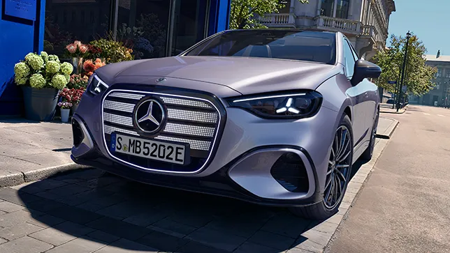 Eine perlmuttfarbene elektrische Mercedes-Benz C-Klasse steht auf einem Parkplatz auf der Straße vor einem Geschäft mit blauer Front.
