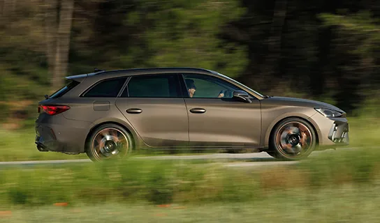 Ein CUPRA Leon Sportstourer in bronze fährt auf einer Straße. Der Vordergrund und Hintergrund verschwimmt.