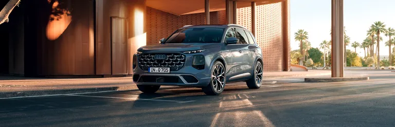 Audi Q7 SUV steht vor modernem Gebäude mit Säulen und Palmen im Hintergrund