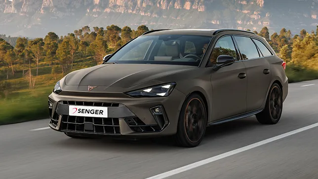 Ein CUPRA Leon Sportstourer in bronze fährt auf einer Straße. Im Hintergrund ist ein Wald und Berge.