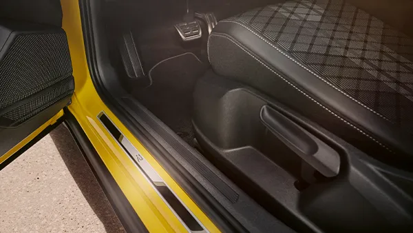 Innenraum eines VW T-Cross mit gelber Einstiegsleiste und Stoffautositz mit Muster