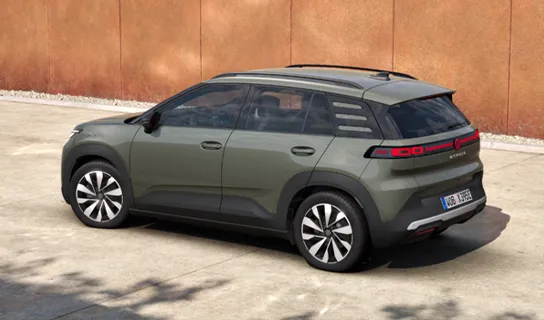 Ein VW ID. Cross in grün metallic steht vor einer rostfarbenen Wand.