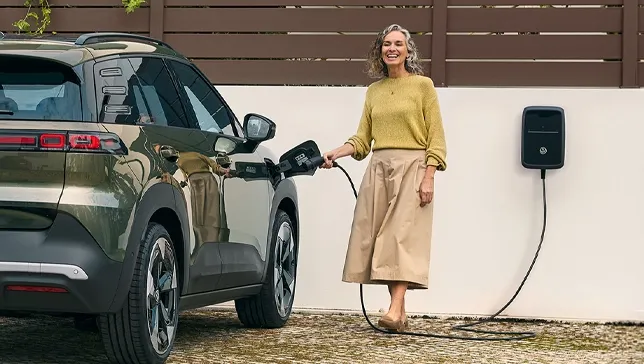Frau lädt Elektroauto an einer Wallbox