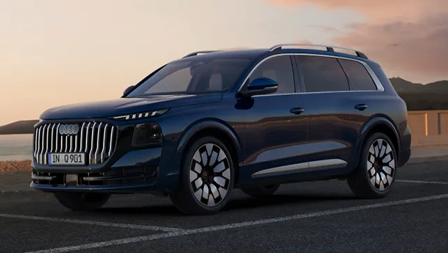 Ein dunkelblauer Audi Q9 SUV steht auf einem Parkplatz an einer Küste mit Bergen im Hintergrund bei Sonnenuntergang.