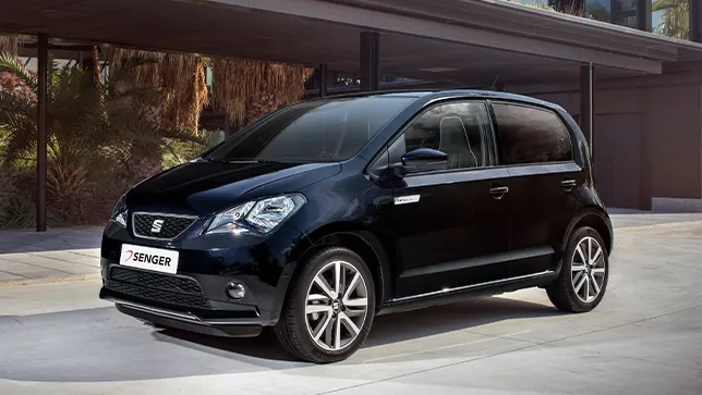 Ein schwarzer SEAT Mii electric steht vor einem modernen Wohnhaus mit Carport.