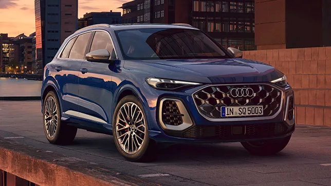 Seitliche Ansicht eines blauen Audi SQ5 auf einer Straße am Wasser bei Sonnenuntergang.