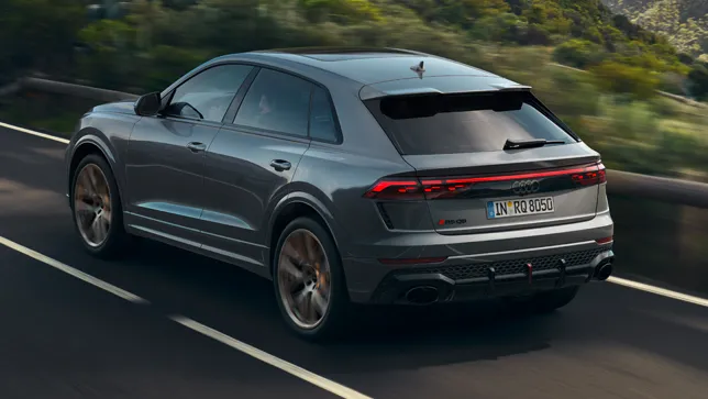 Ein silberner Audi RS Q8 fährt auf einer kurvigen Bergstraße.