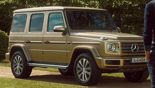 Eine Detailaufnahme der Front einer goldenen Mercedes-Benz-G-Klasse.
