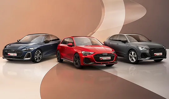 Drei Audi-Fahrzeuge in Schwarz, Rot und Dunkelgrau stehen nebeneinander auf einer spiegelnden Fläche mit beigen und braunen Bögen auf dem Boden und an der Wand.
