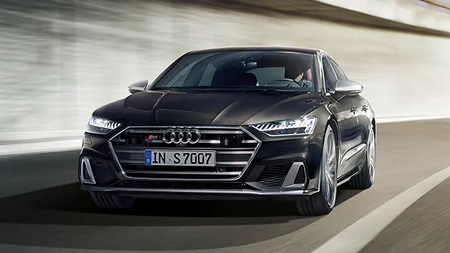 Ein schwarzer Audi A7 Sportback fährt auf einer kurvigen Straße vor einer Betonwand.