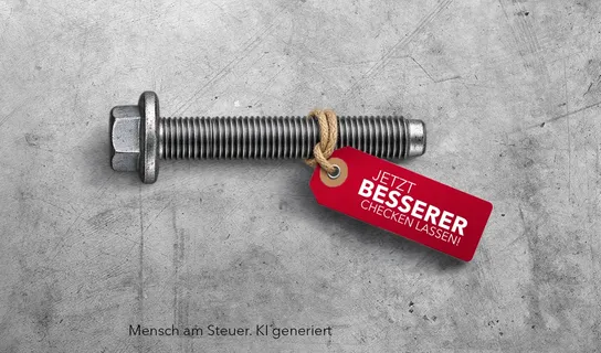 Eine Schraube mit sechseckigem Kopf liegt auf einem Betonboden und trägt ein rotes Etikett mit dem weißen Text 'JETZT BESSERER CHECKEN LASSEN!'
